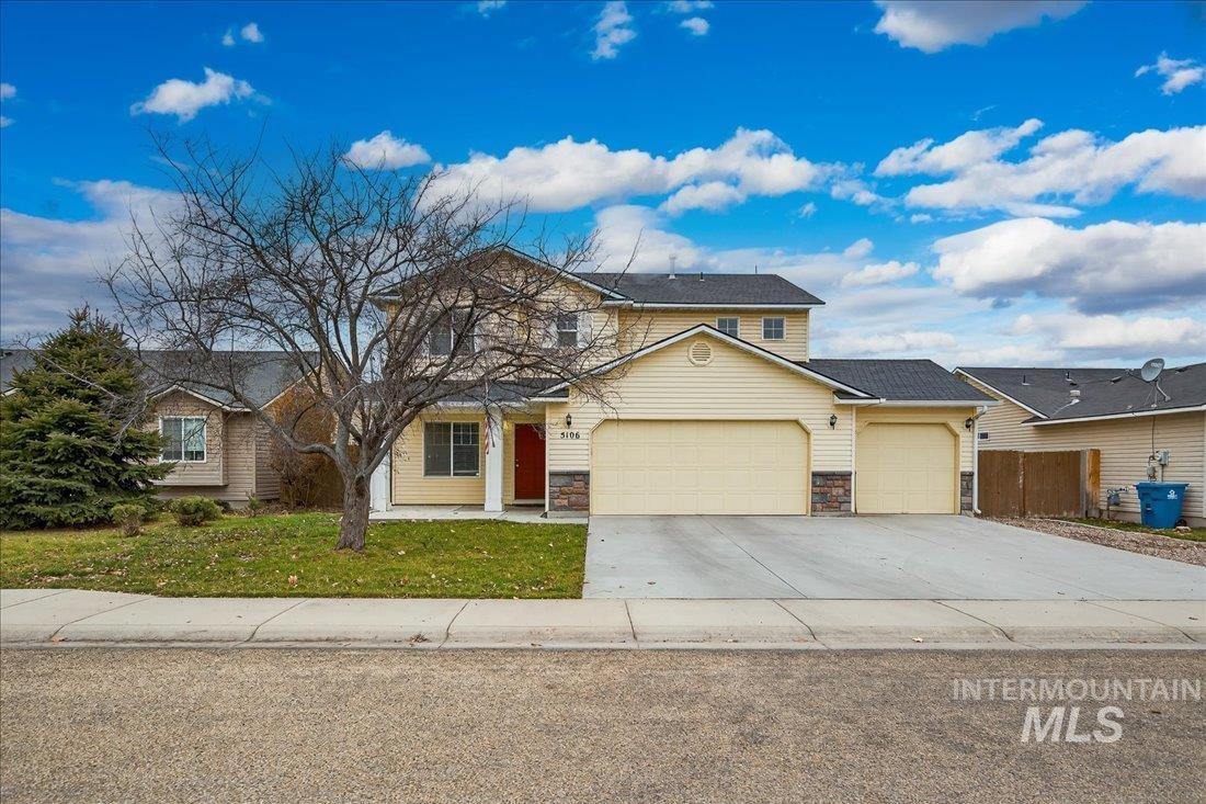 Traditional-style house with an attached garage, driveway, stone siding, and a front yard