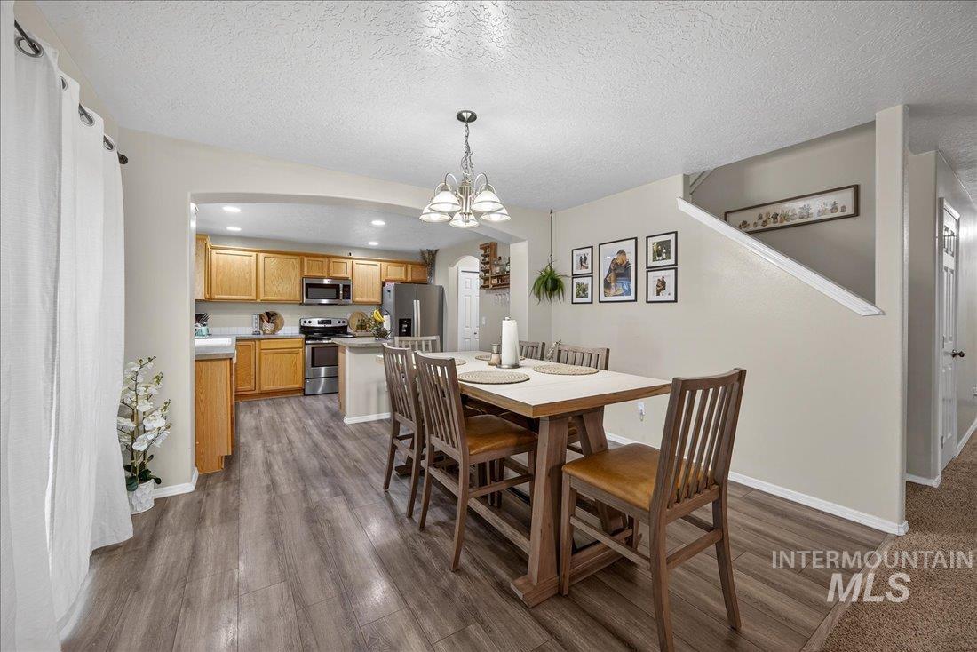 5106 Lathrop Place, Unit 19517 Caldwell, ID 83607 - Photo 15 of 29 Dining area with recessed lighting, dark wood-style floors, a chandelier, a textured ceiling, and arched walkways