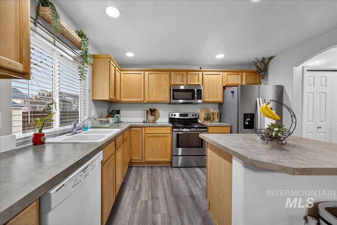 5106 Lathrop Place, Unit 19517 Caldwell, ID 83607 - Photo 18 of 29 Kitchen with appliances with stainless steel finishes, recessed lighting, dark wood-style floors, arched walkways, and a textured ceiling