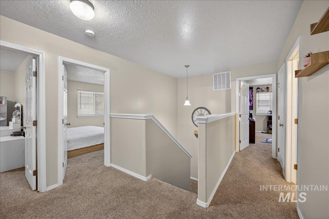 5106 Lathrop Place, Unit 19517 Caldwell, ID 83607 - Photo 23 of 29 Corridor featuring an upstairs landing, a textured ceiling, light carpet, and plenty of natural light
