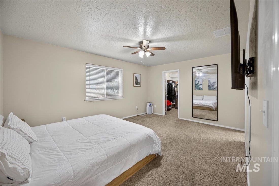 5106 Lathrop Place, Unit 19517 Caldwell, ID 83607 - Photo 26 of 29 Bedroom featuring carpet, a walk in closet, a textured ceiling, and a ceiling fan