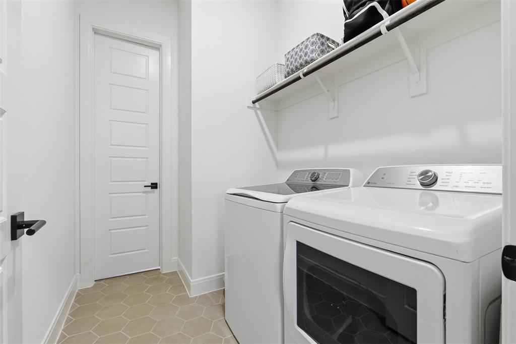 15413 Short Rdg Lane Fort Worth, TX 76008 - Photo 32 of 39 Laundry area featuring hexagon tile flooring, white shaker-style doors with matte black hardware, and an overhead storage shelf