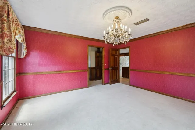 a view of an empty room with a window and a kitchen