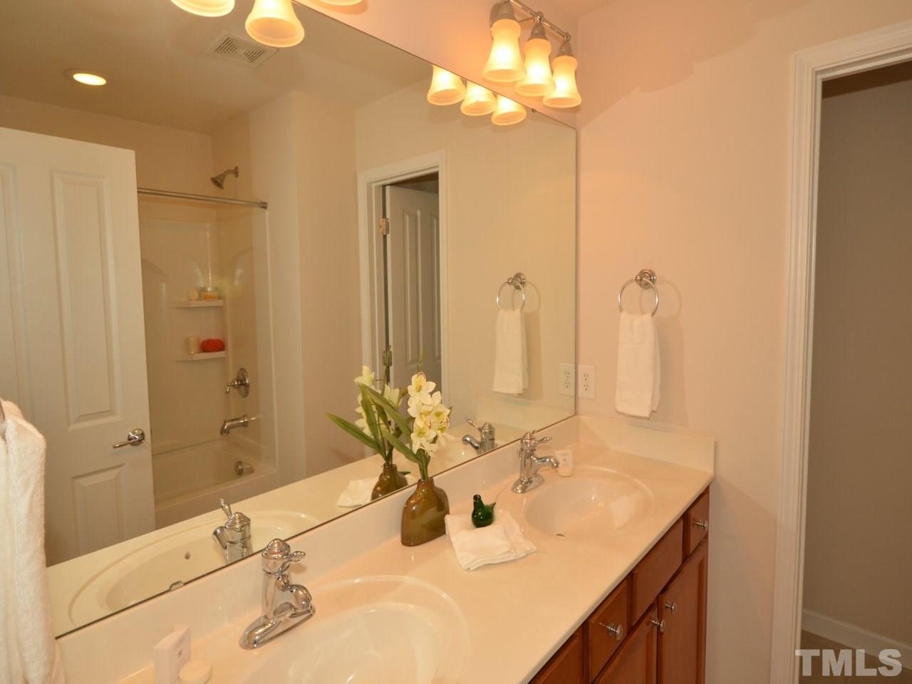 8709 Owl Roost Place Raleigh, NC 27617 - Photo 10 of 25 Upgraded double bowl sink with comfort, raised height vanity cabinetry plus shapely frosted glass lighting distinguishes this spa bath.