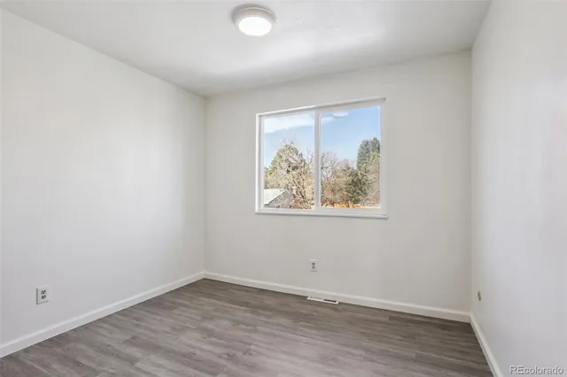 an empty room with wooden floor and window