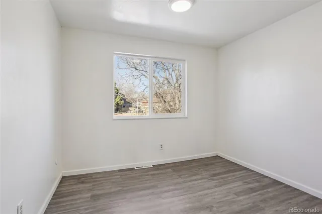 an empty room with wooden floor and window