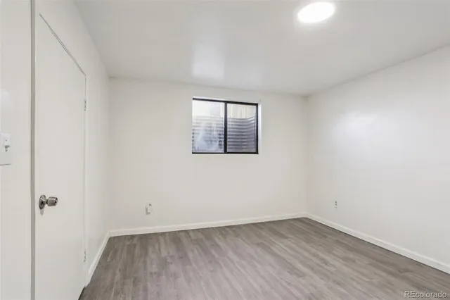 an empty room with wooden floor and window