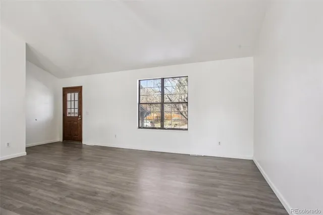 an empty room with wooden floor and window