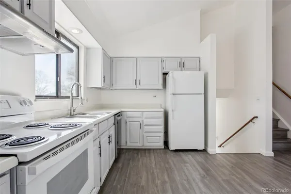 a kitchen with a sink a stove a refrigerator and white cabinets