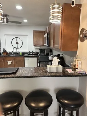a kitchen with stainless steel appliances granite countertop a sink a stove a dining table and chairs