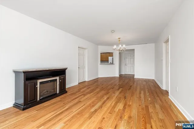 a view of empty room with wooden floor and fireplace