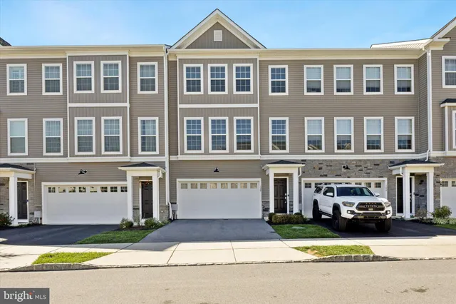 a front view of a building with a garden and car parked