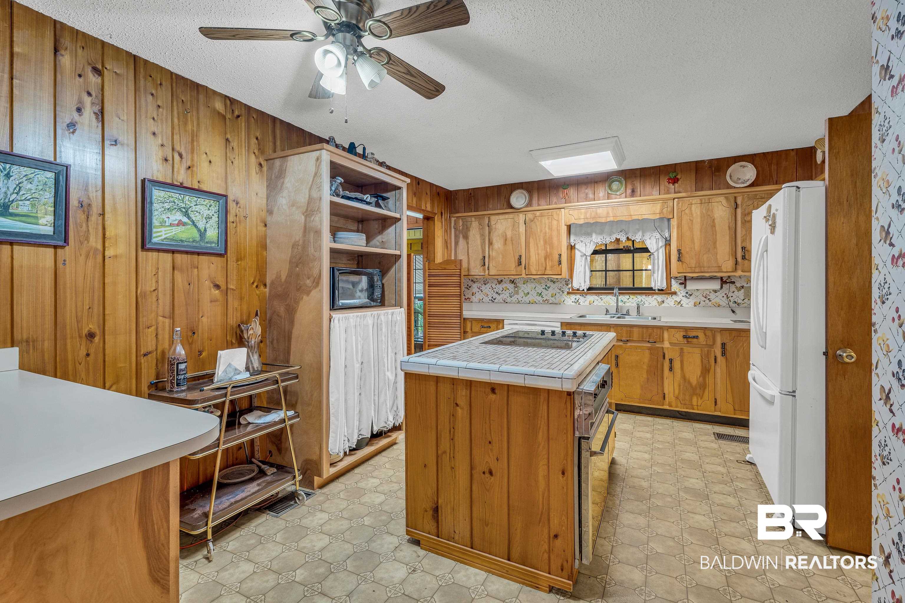 72075 Highway 59 Little River, AL 36550 - Photo 12 of 40 Kitchen with wooden walls, brown cabinets, open shelves, tile counters, and black appliances