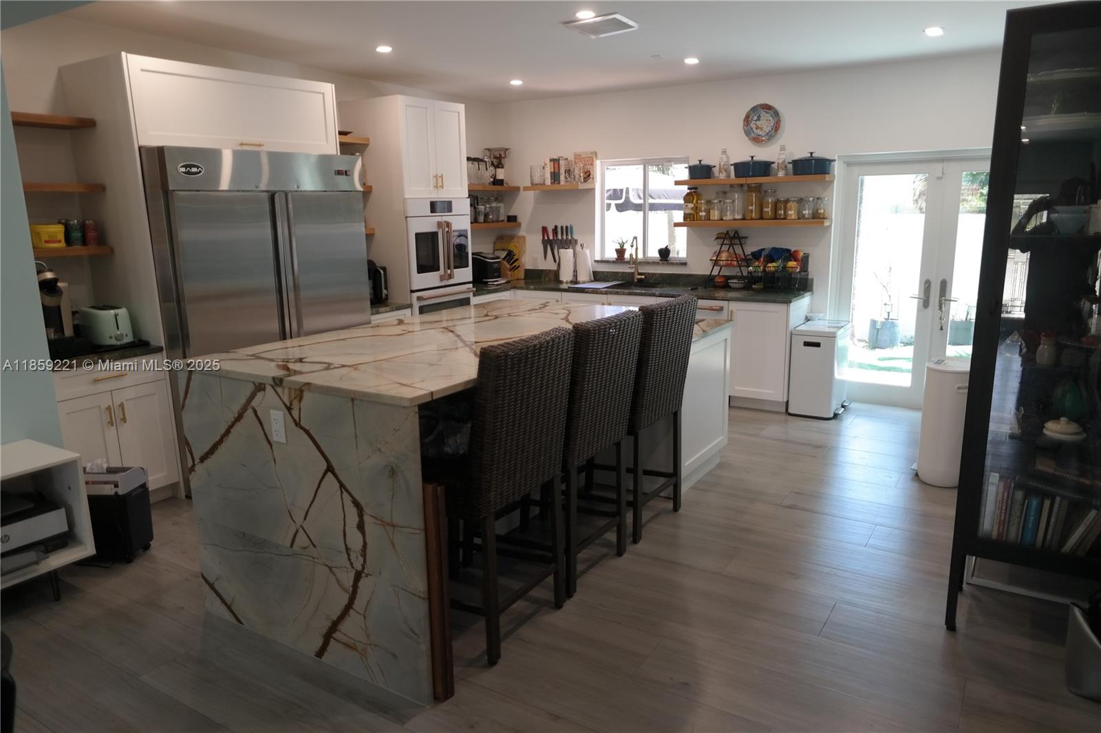 524 Northeast 27th Drive Wilton Manors, FL 33334 - Photo 11 of 95 a kitchen with stainless steel appliances kitchen island granite countertop a table chairs refrigerator and sink