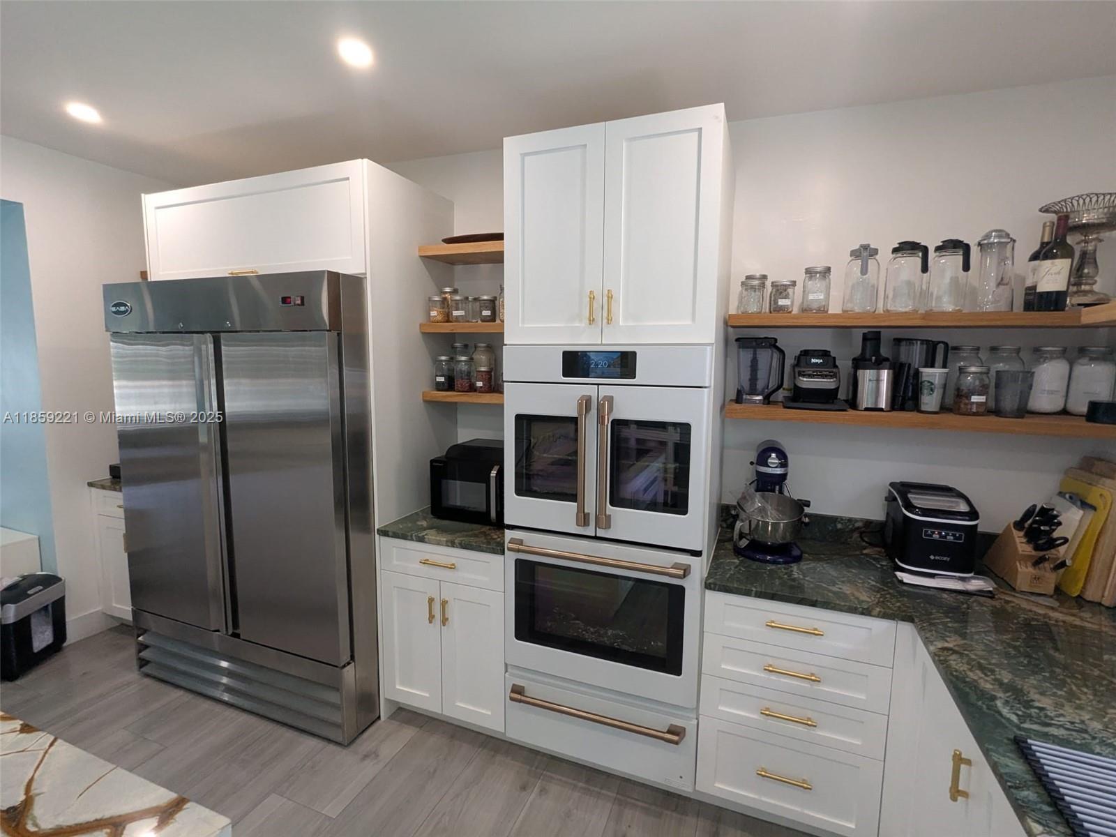 524 Northeast 27th Drive Wilton Manors, FL 33334 - Photo 9 of 95 Charming kitchen and oversized Saba double-door stainless steel fridge with warm, coordinated lighting that creates a cozy atmosphere.