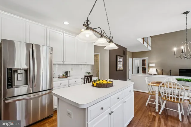 a kitchen with stainless steel appliances a sink a stove a refrigerator cabinets and chairs