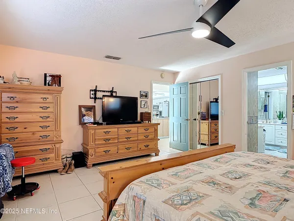 a bedroom with a bed and a large mirror on the dresser