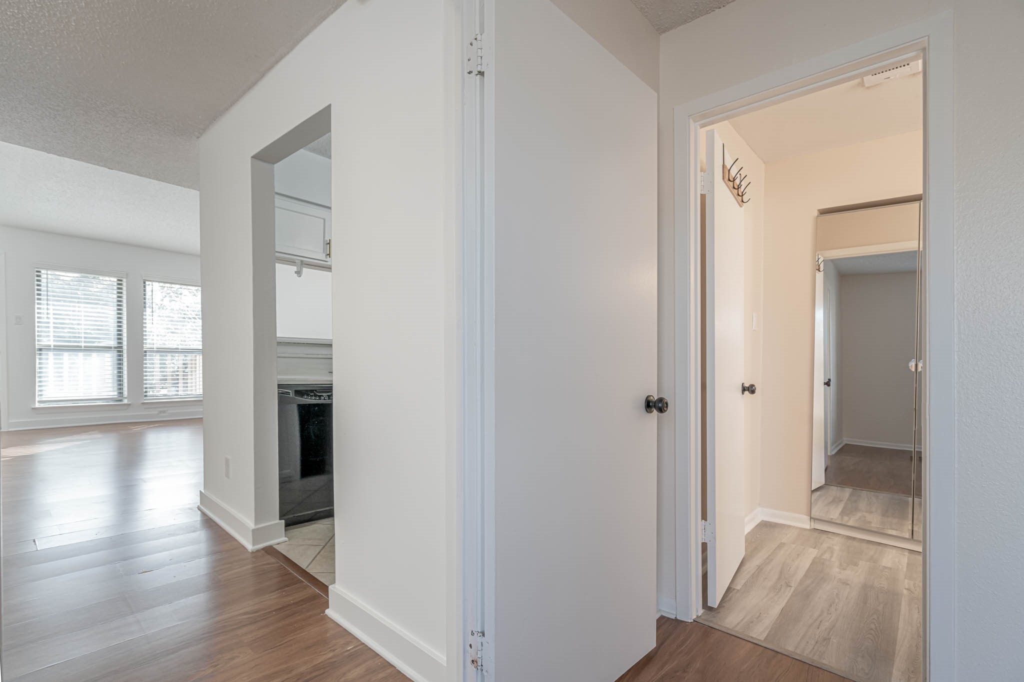 2277 South Kirkwood Road, Unit 4/808 Houston, TX 77077 - Photo 15 of 23 Bright and airy interior featuring an open layout with laminate flooring. The kitchen is partially visible with modern appliances, and there's a hallway leading to a room with mirrored closet doors. Large windows provide ample natural light.
