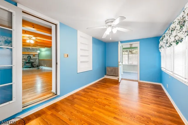 a view of an empty room with window and wooden floor