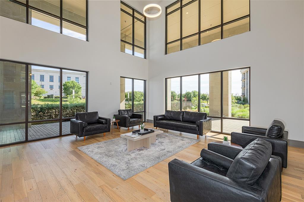 2700 Old Denton Road, Unit 1044 Carrollton, TX 75007 - Photo 26 of 33 Spacious open-concept room featuring a high ceiling, wood-finish flooring, and expansive floor-to-ceiling windows