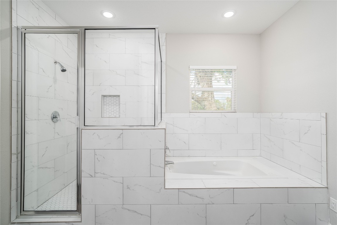231 McCormick Street Columbus, TX 78934 - Photo 16 of 27 Primary Bathroom – Luxurious soaking tub and separate glass-enclosed shower, complemented by elegant tile work throughout.