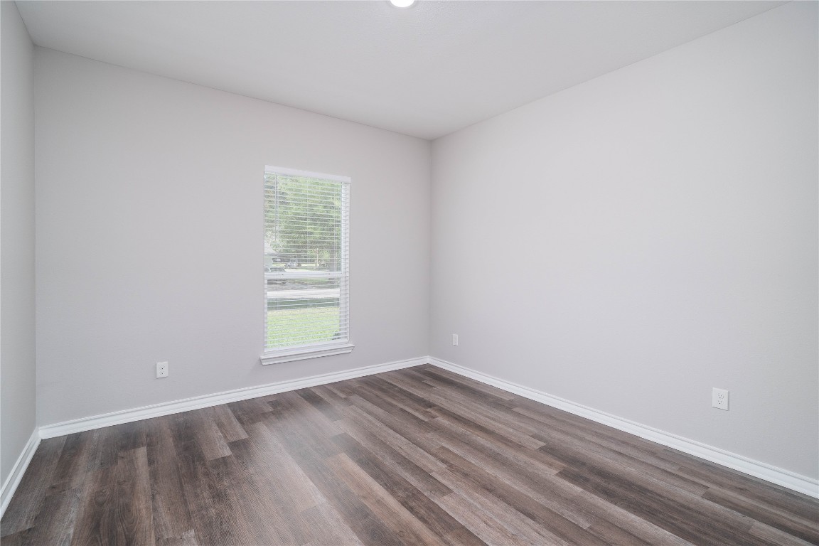 231 McCormick Street Columbus, TX 78934 - Photo 18 of 27 Bedroom – Bright and inviting bedroom featuring wood-look flooring, neutral tones, and a large window that brings in abundant natural light.