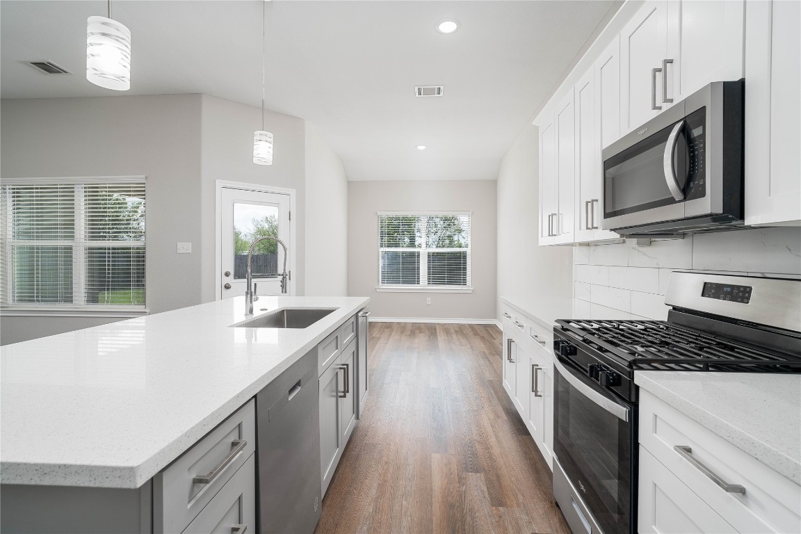 231 McCormick Street Columbus, TX 78934 - Photo 5 of 27 Kitchen & Breakfast Area – Seamless flow from the kitchen to the breakfast area, highlighted by natural light, sleek finishes, and an oversized island with sink and bar seating.
