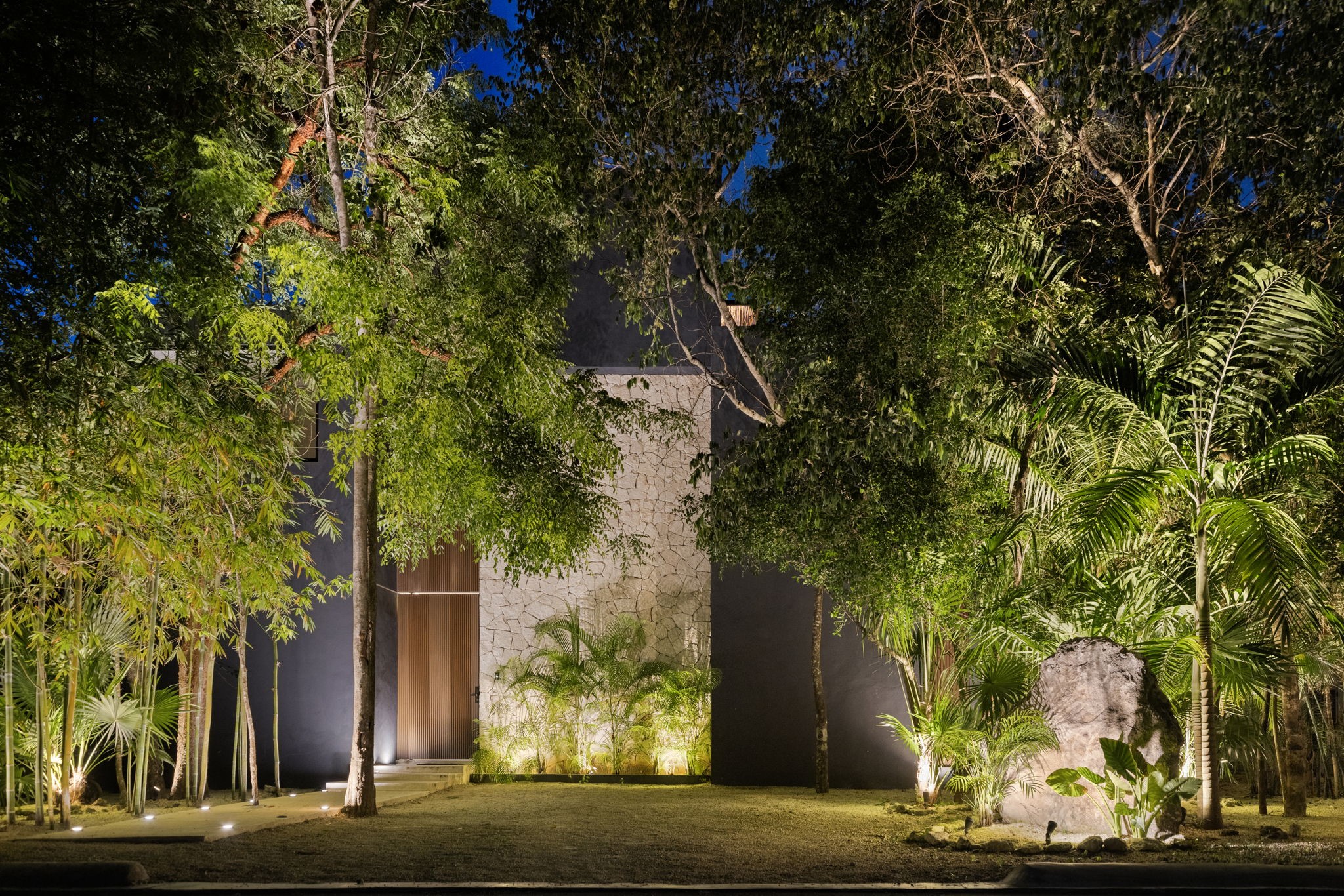 6 Country Club, Unit 4 Nome, TX 77629 - Photo 3 of 45 Discover unparalleled privacy and contemporary elegance behind this architectural facade enveloped by Cozumel's lush tropical jungle. Expertly designed landscape lighting illuminates native flora, textured stone accenting, and a grand wooden entrance to welcome you home in style.