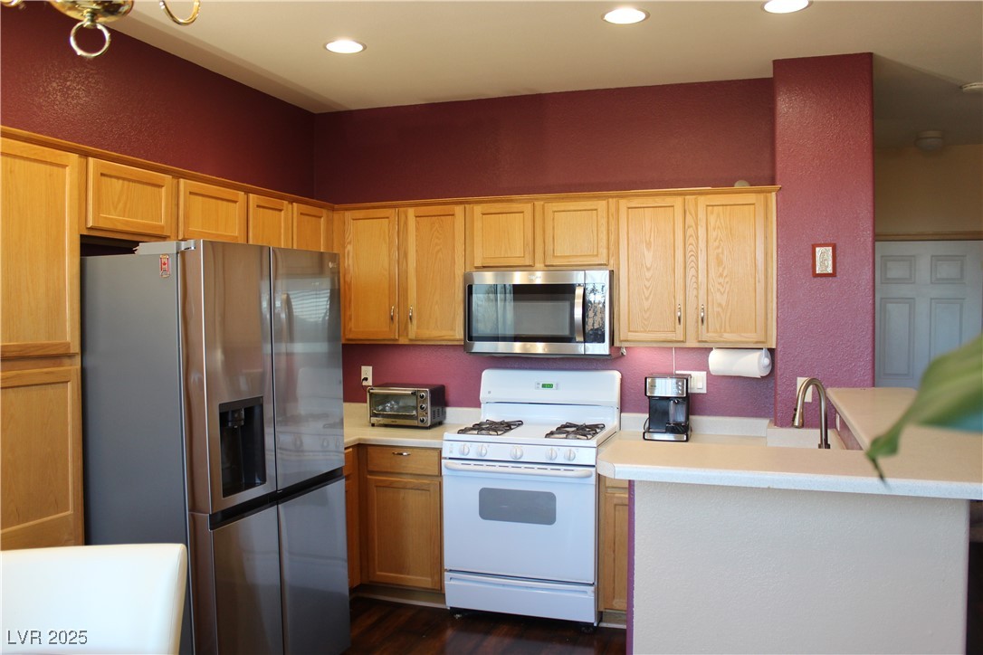 207 Priority Point Street Henderson, NV 89012 - Photo 8 of 38 Kitchen with stainless steel appliances, light countertops, a textured wall, a peninsula, and recessed lighting