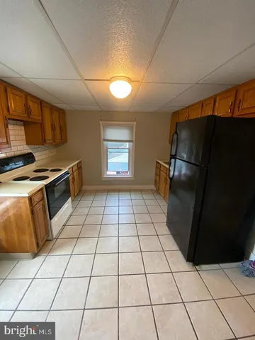 a kitchen with granite countertop a stove a refrigerator a sink a counter top space and cabinets