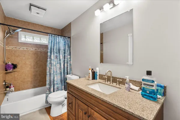a bathroom with a granite countertop sink toilet mirror and shower