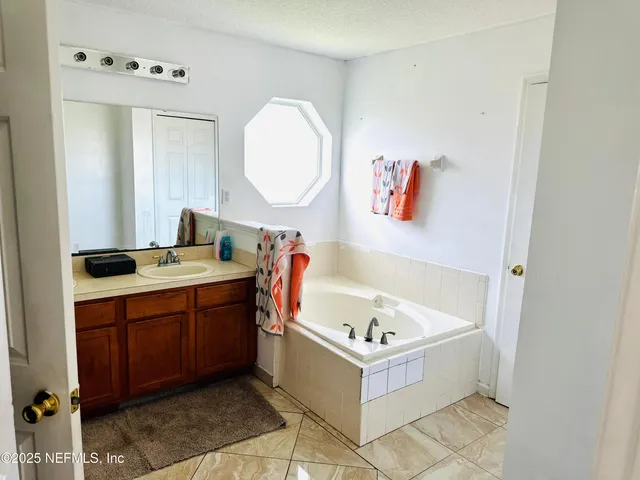 a bathroom with a tub sink and mirror