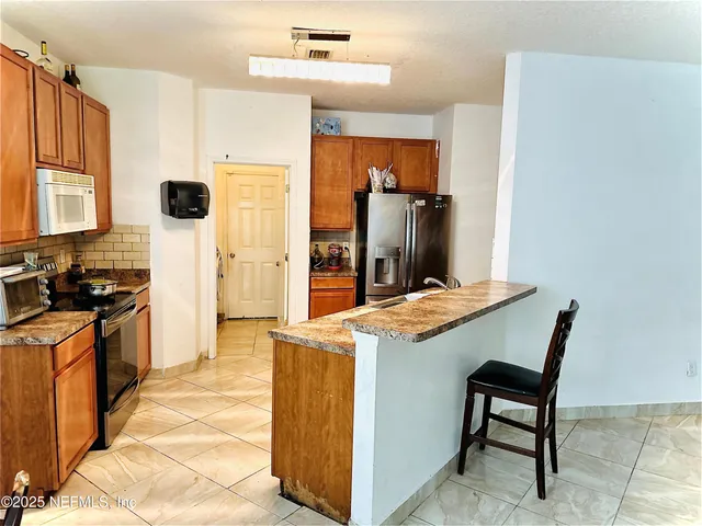 a living room with stainless steel appliances kitchen island granite countertop furniture and a refrigerator