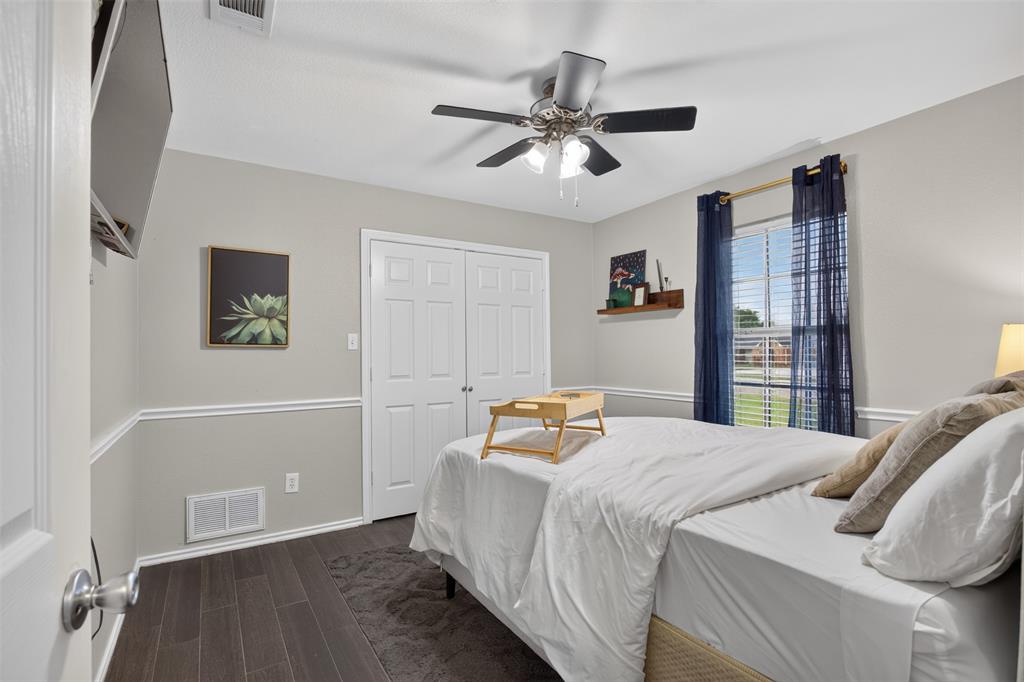 100 Radecke Road Krum, TX 76249 - Photo 18 of 29 Bedroom featuring wood-finish flooring, white trim, a double-door closet, and a ceiling fan with integrated lighting
