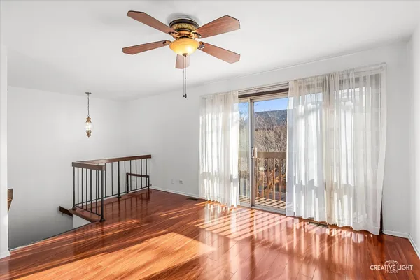 a view of a room with wooden floor and a chandelier fan