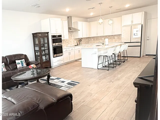 a living room with stainless steel appliances furniture and a kitchen view