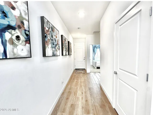 a view of a hallway with wooden floor and a bathroom
