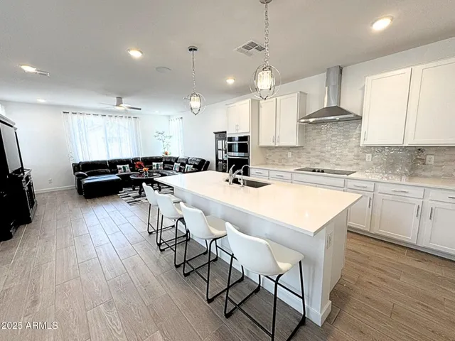 a kitchen with stainless steel appliances a dining table chairs sink and wooden floor