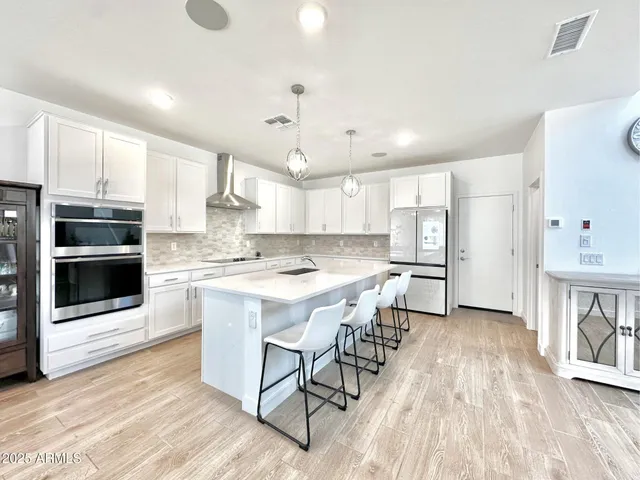 a kitchen with stainless steel appliances kitchen island granite countertop a stove a sink a refrigerator and a cabinets