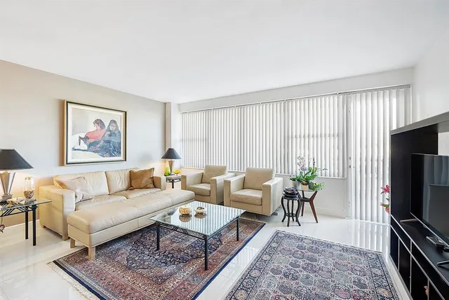 a living room with furniture a rug a flat screen tv and a large window