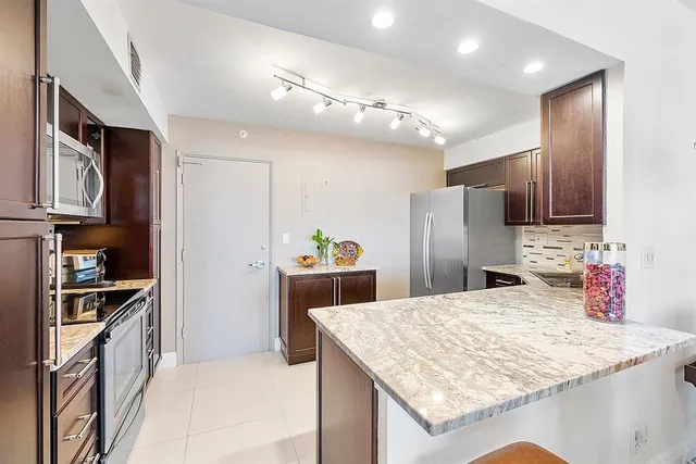 a kitchen with stainless steel appliances kitchen island granite countertop a refrigerator and a stove top oven