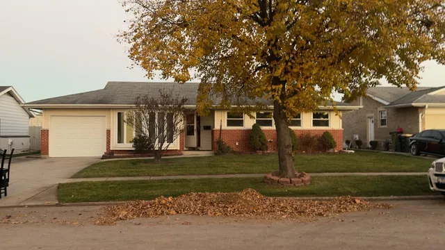 a view of a white house next to a yard with big trees