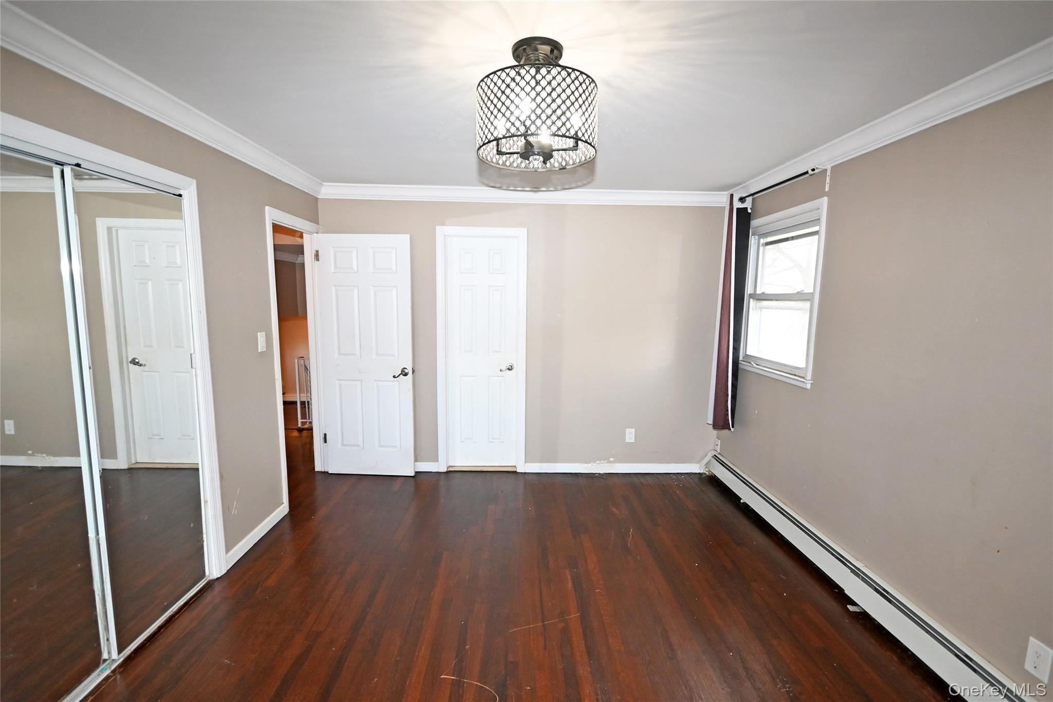 89 Osborne Road West Hempstead, NY 11552 - Photo 13 of 50 Unfurnished bedroom featuring a baseboard heating unit, dark wood-style floors, ornamental molding, a closet, and a chandelier