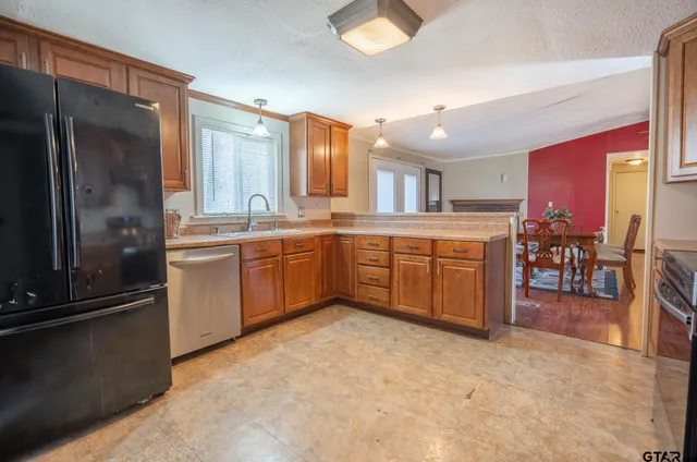 a kitchen with stainless steel appliances granite countertop a stove top oven a sink dishwasher a dining table and chairs with wooden floor