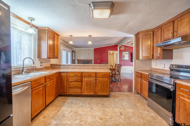 a kitchen with granite countertop a stove a sink and a refrigerator