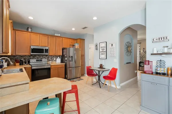 a kitchen with stainless steel appliances kitchen island granite countertop a refrigerator a sink dishwasher stove with dining table and chairs