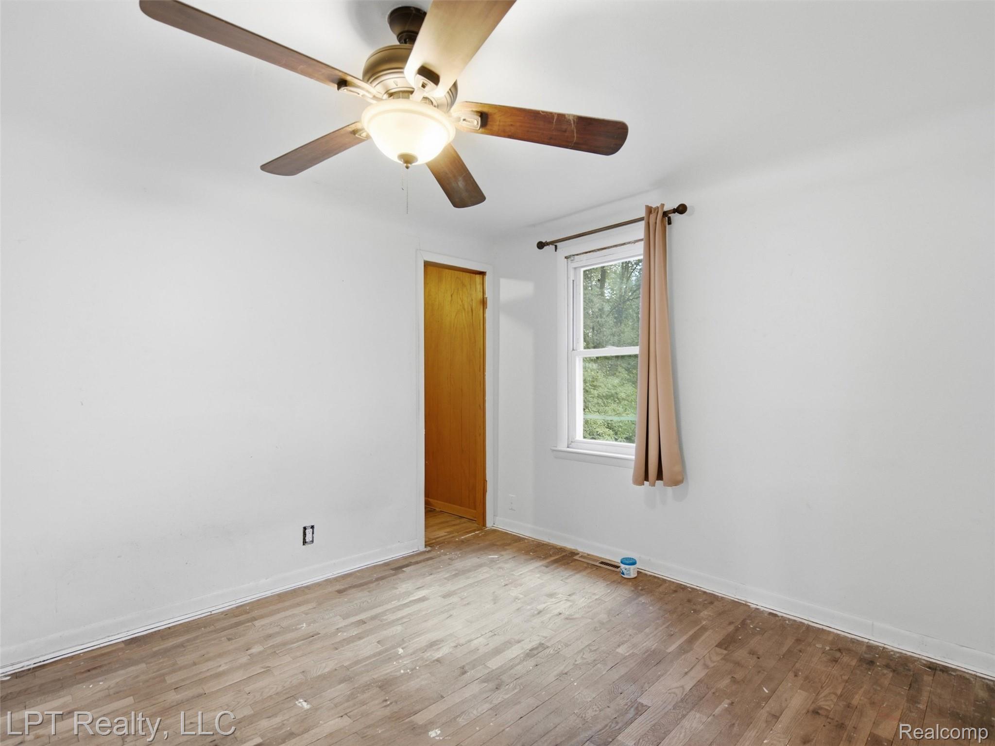 3385 North Genesee Road Flint, MI 48506 - Photo 10 of 24 Hardwood flooring, white walls, and a ceiling fan with integrated lighting
