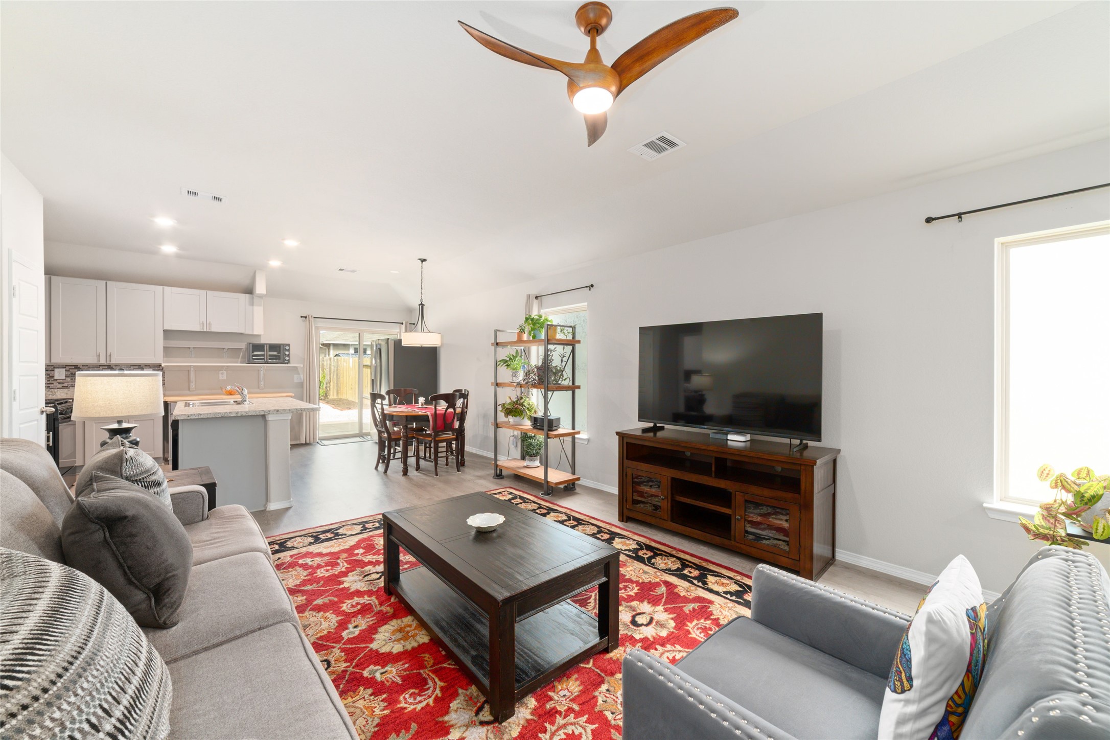 14232 Shasta Ridge Drive Conroe, TX 77303 - Photo 6 of 26 Spacious main living area with large windows and a ceiling fan, creating an open feel that flows naturally into the dining and kitchen areas.