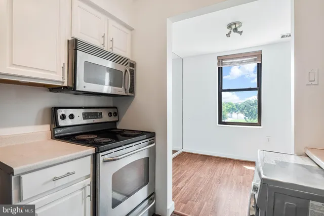 a kitchen with granite countertop cabinets stainless steel appliances and a wooden floor
