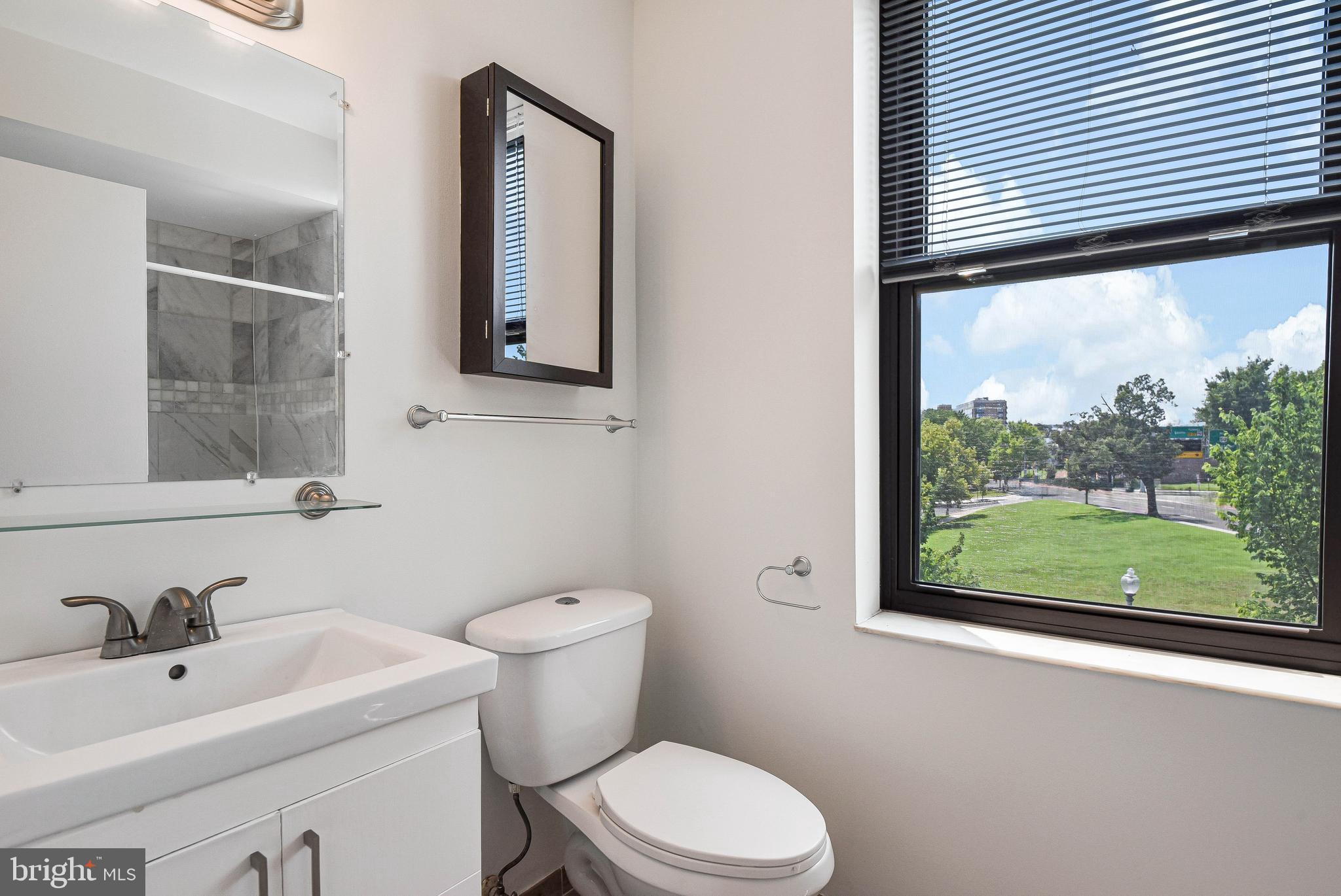 80 New York Avenue Northwest, Unit 303 Washington, DC 20001 - Photo 18 of 27 a bathroom with a toilet a sink a mirror and window